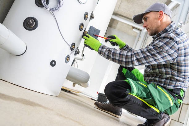 Techniker wartet ein Warmwasserspeicher im Hauswirtschaftsraum eines Wohnhauses